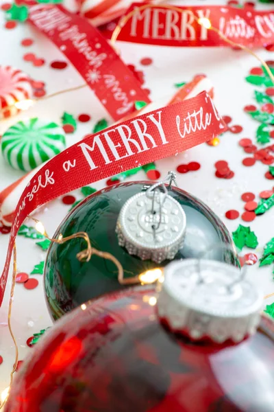 Decoration with red fluid filled Christmas ornament ball and two green filled ornament balls surrounded by a red Have Yourself A Merry Christmas ribbon, a set of Christmas lights and peppermint candy