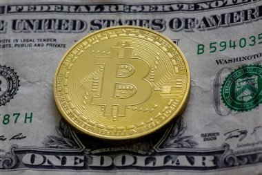 Bitcoins yığın üstüne siyah bir tabloda bir dolarlık banknot.