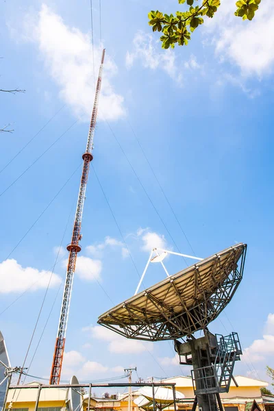 Signal Tower and satellite dish The sky is big and the clouds are white as the backdrop.