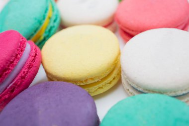 Yakın çekim fotoğraf renkli magaroon bir beyaz seramik tabak içinde yer alıyor. Kahve masasıyla zarif mermer yemek masası.