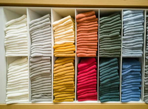 Pamuk T-shirt showroom, renkli elbise dolabında, katlanmış düzgünce katlanmış renkli elbise düzgünce giyinmiş, raflar ve büyük mağazalarda, bir satır renkli gömlek çok renkli giysiler.