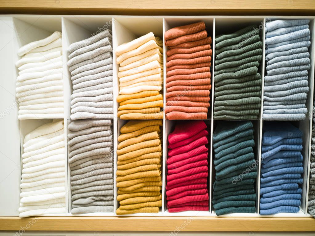 Cotton T-shirt folded neatly in the showroom,Colorful clothes folded in the cabinet,Colorful clothes neatly dressed,Shelves and multi-colored clothes in large stores,A row of colorful shirts.