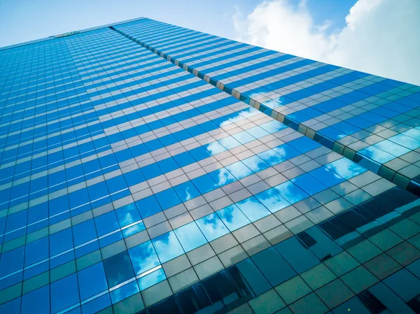 Mirror reflection of tall buildings.Shadow reflects the white clouds and the blue skies of glass of tall buildings.