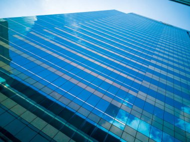 Yüksek binalar ayna yansıması. Beyaz bulutlar ve yüksek binalar bardak mavi gökyüzü gölge yansıtır.