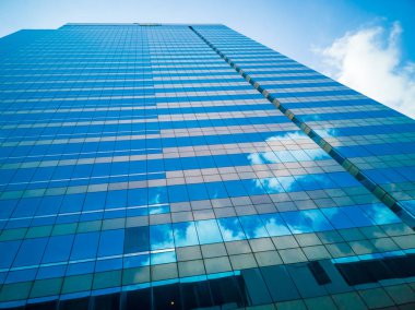 Yüksek binalar ayna yansıması. Beyaz bulutlar ve yüksek binalar bardak mavi gökyüzü gölge yansıtır.