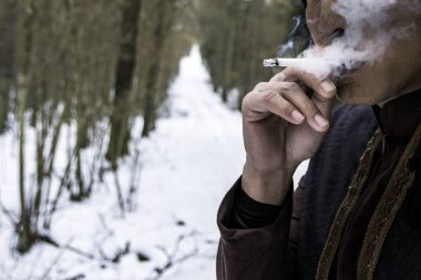 Kar larla kaplı çam ormanında sert elleriyle sigara çakma içen adamı kapatın