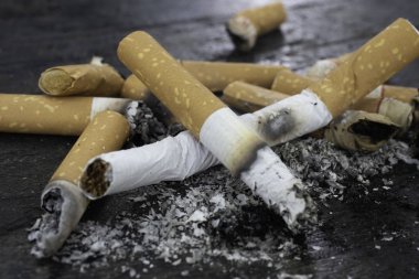 Sigaralar yakıldı ve sigara lar pompalandı. Dünya Tütüne Hayır Günü her yıl 31 Mayıs'a denk geliyor. Duman sigaralar parçalandı,Yakın çekim Siyah ahşap zemin.sığ odak etkisi