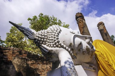 Phra Nakhon Si Ayutthaya Tarihi Parkı'ndaki Wat Yai Chai Mongkhon Tapınağı, Sarı cüppelerle kaplı beyaz bir Buda heykeli ile Phra Nakhon Si Ayutthaya, Tayland'daki antik kalıntıların ortasında poz verirken.