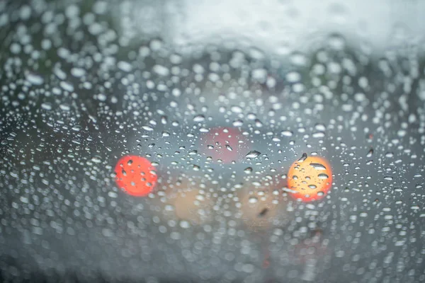 Spot focus  Drops of rain flowing into the car glass At the time of rain Blurred background as a car taillight.