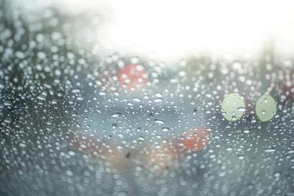 Spot focus  Drops of rain flowing into the car glass At the time of rain Blurred background as a car taillight.