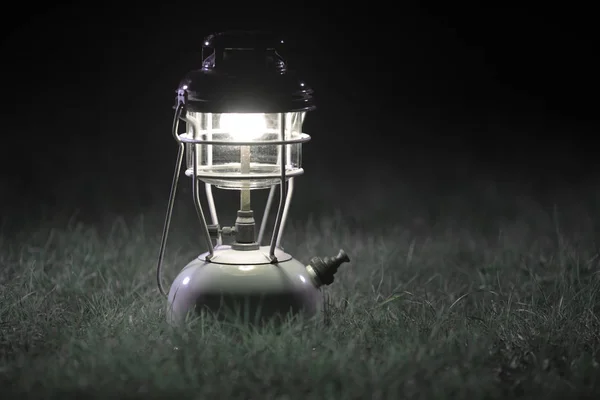 Oil Lamp Lighting up the Darkness or Burning kerosene lamp On the green lawn, concept lighting. Selective focus