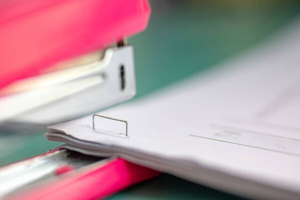 The pink stapler does not pierce through many sheets of paper.sh