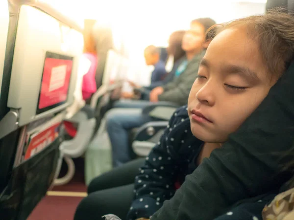 Kız ekonomi sınıfında annenin kollarında uyuyor 