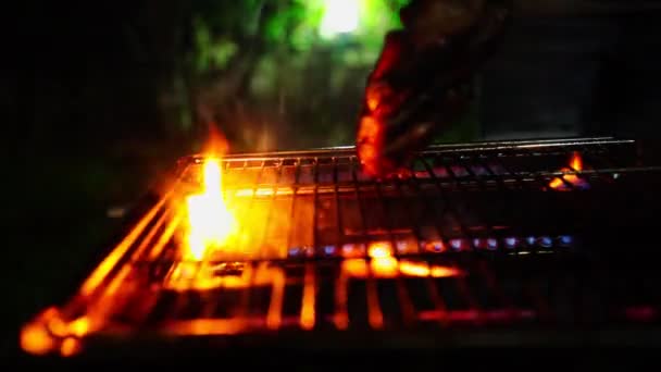 黒地に火の多いグリルから肉片を飛び散らせる — ストック動画