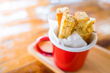 Sarımsaklı ekmeğin sığ derinliği Tayland ahşap masasında kırmızı bir diş minesi kabının içinde.