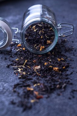 Siyah çay koyu arka plan üzerinde bir cam kavanoza doğal katkı maddeleri ile