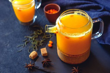 Deniz cehri çay turuncu renkte bir cam bardak taze deniz topalak meyveleri ile. Bitkisel vitamin çay.