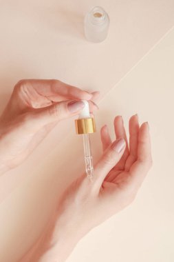 Güzel bakımlı kadının elleri ve hafif bir arka plan üzerinde serum. Kışın temiz ve yumuşak ciltler için besleyici yağ.