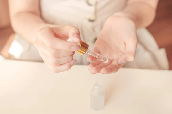 Mooie verzorgde vrouw handen met serum op een lichte achtergrond. Voedende olie voor een schone en zachte huid in de winter. — Stockfoto