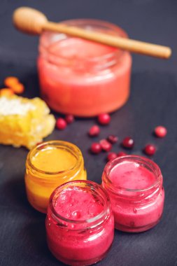 Çilek ve meyve ile kavanozda kremalı bal, siyah taş arka plan üzerine dipper