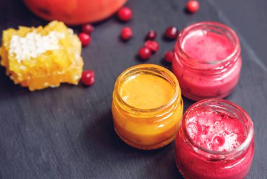 Çilek ve meyve ile kavanozda kremalı bal, siyah taş arka plan üzerine dipper