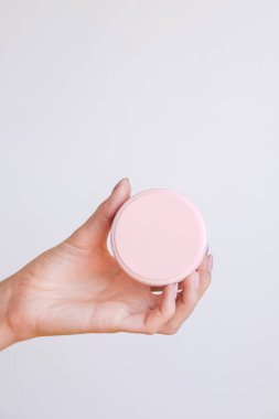 Güzel bakımlı kadın elleri, hafif bir arka planda vücut kremi ve cilt kremi.