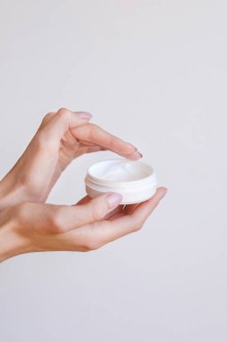 Güzel bakımlı kadın elleri, hafif bir arka planda vücut kremi ve cilt kremi.