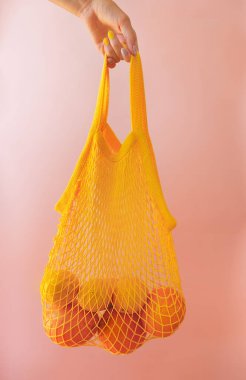Pembe tuval arka planda limonlu ağ alışveriş torbası.