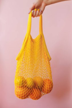 Pembe tuval arka planda limonlu ağ alışveriş torbası.