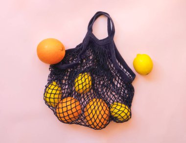 Pembe tuval arka planda limonlu ağ alışveriş torbası.