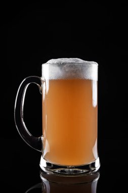 Bir kupa köpüklü bira koyu arka planda izole edilmiş.