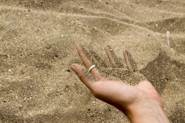 Sand running down from man's hand at the beach — Stock Photo, Image