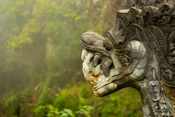 Ancient fantasy dragon statue in a forest.