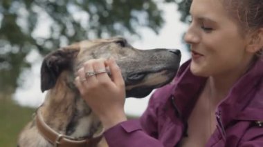 Güzel mutlu genç kadın onu sevgi dolu & sadık evde beslenen hayvan köpek parkında okşayarak