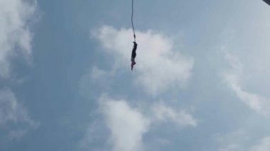 Bungee jumping karşı mavi gökyüzü (ağır çekim) - anonim kadın Siilhouette