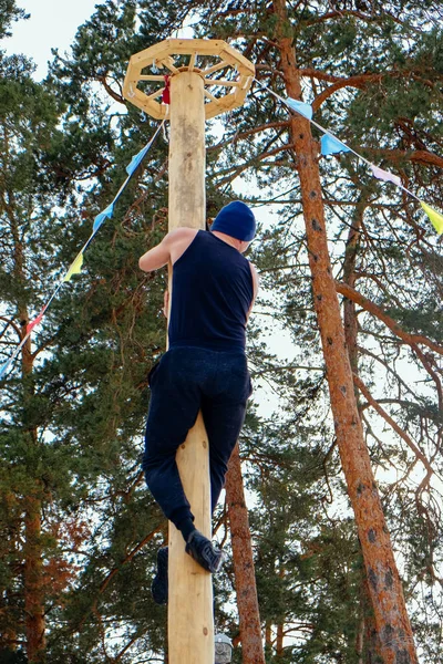 Shrovetide'de bir adam sütuna tırmanıyor.