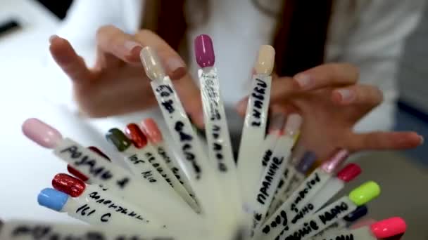 Procedimento de manicure. Procedimento de manicure feminina, seleção da cor da laca pela paleta de cores na mão feminina — Vídeo de Stock