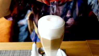 Cup of coffee close up. The girl pours sugar into a cup.