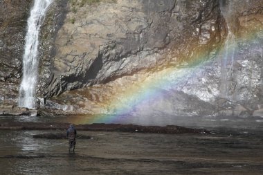Arka planda gökkuşağı ile su Montmorency Falls, Quebec balıkçılık yanında adam