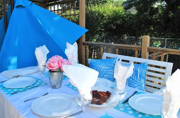 Açık yemek masası ile yemekler, Gözlük, peçete ve bankta mavi yastık