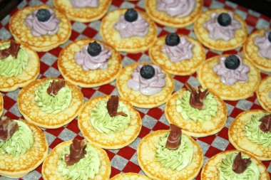 Damalı kağıdın üzerine girdaplı krem peynir ve meyve ile küçük gözleme üzerinde mezeler