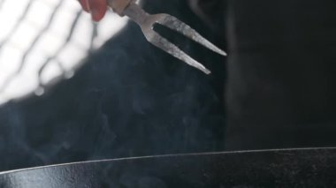 Büyük çatallı, ızgaralı, ağır çekimde bir şefin eli.