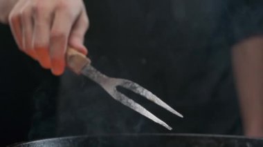 Büyük çatallı, ızgaralı, ağır çekimde bir şefin eli.
