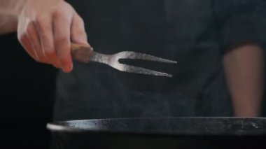 Büyük çatallı, ızgaralı, ağır çekimde bir şefin eli.
