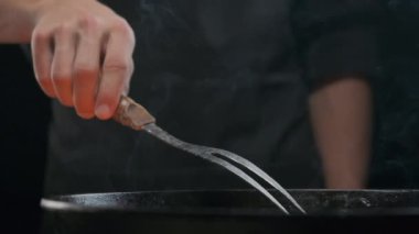 Büyük çatallı, ızgaralı, ağır çekimde bir şefin eli.
