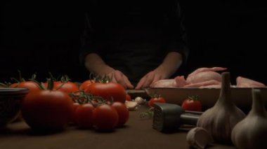 Şef bütün tavuğu sebze ve sarımsak ile masada kızarması için hazırlar.