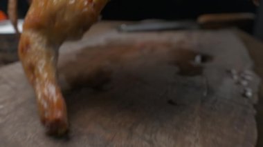 Şef ızgara tavuğu büyük bir bıçakla yavaş çekimde kesmeye hazırlanıyor.