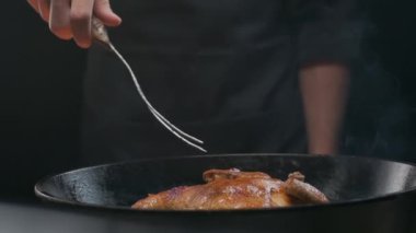 Şef ızgara tavuğu büyük bir çatalla çeviriyor, ağır çekimde.