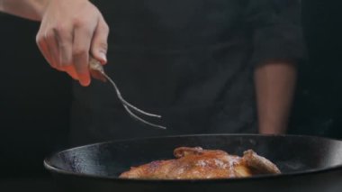 Şef ızgara tavuğu büyük bir çatalla çeviriyor, ağır çekimde.