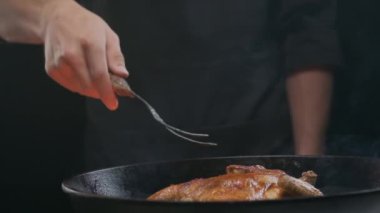Şef ızgara tavuğu büyük bir çatalla çeviriyor, ağır çekimde.